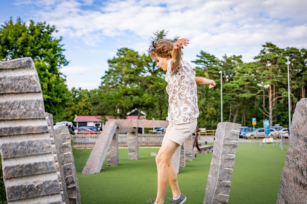 En ung kille mitt i ett hopp på en parkourbana.