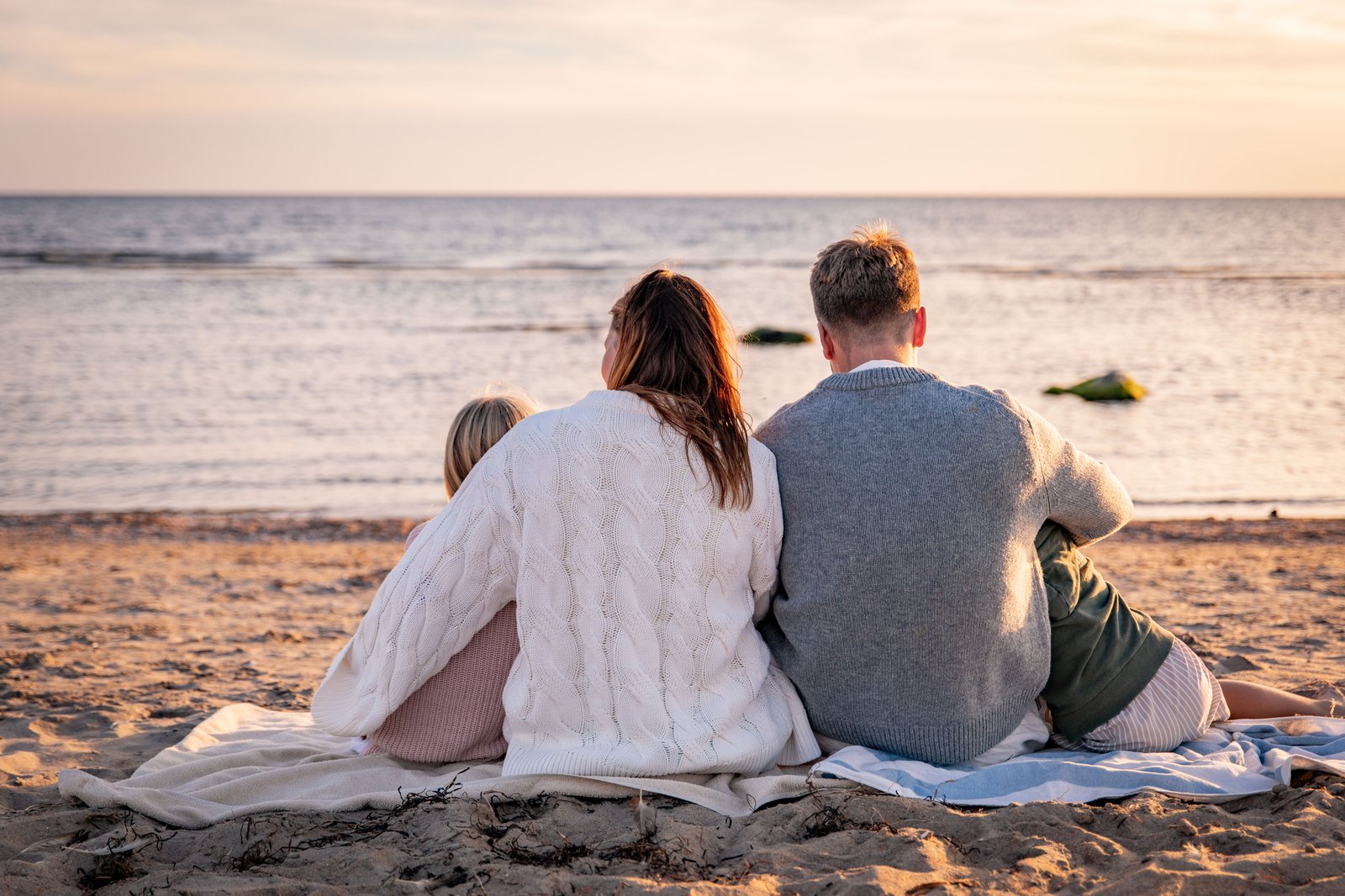 en familj sitter på en filt vid havet